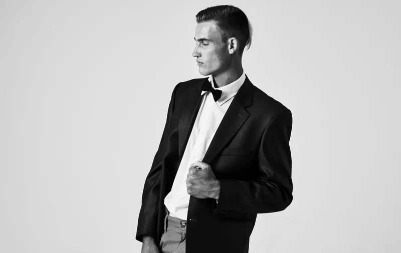 Черно-белая фотография мужчины в пиджаке, рубашке и бабочке на шее