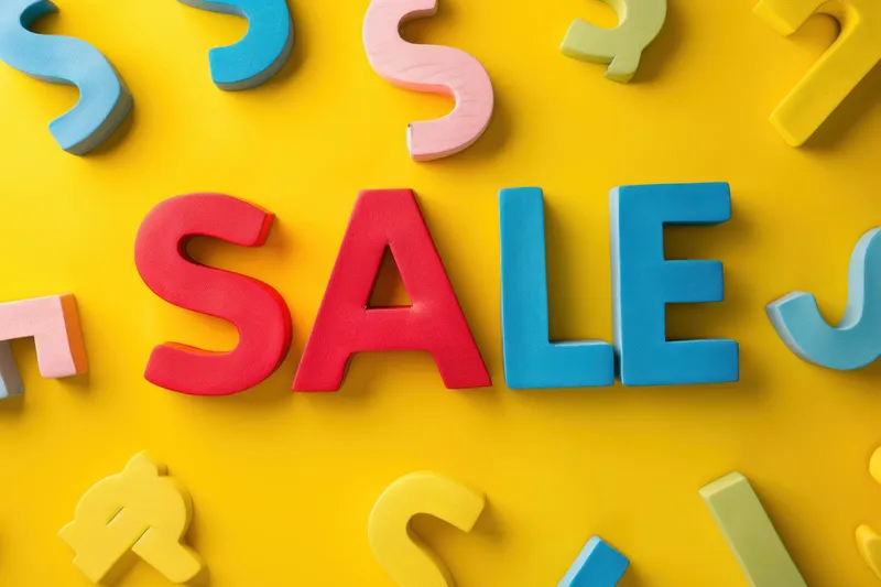 На желтом фоне разноцветные буквы и цифры окружают слово sale в деловой тематике