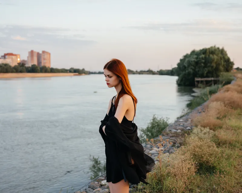 Красивая женщина в чёрной одежде позирует на фоне природного пейзажа во время прогулки