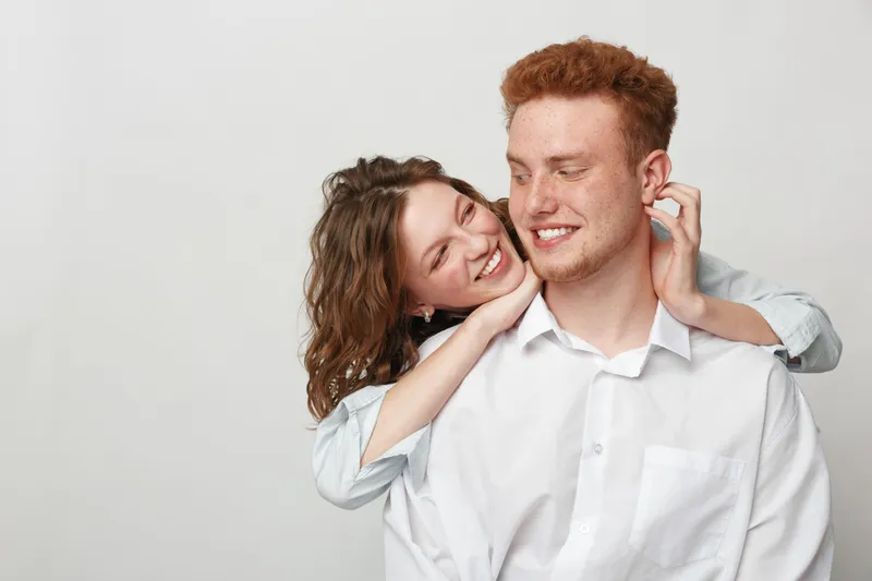 Happy young couple with red hair smiling and embracing each other on white background. Concept of love, relationship, affection, and joyful moments together.