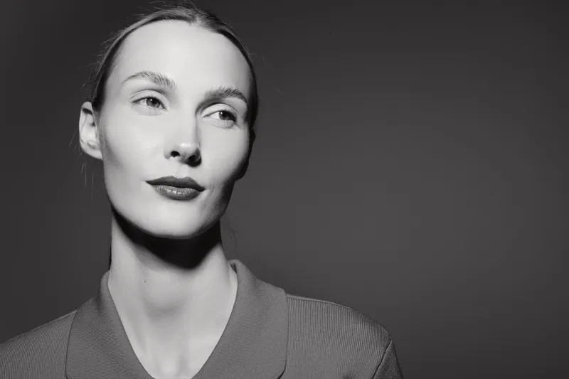 Portrait of a young white woman with fair skin looking sideways in black and white. Minimalistic studio lighting highlights her calm and confident expression.