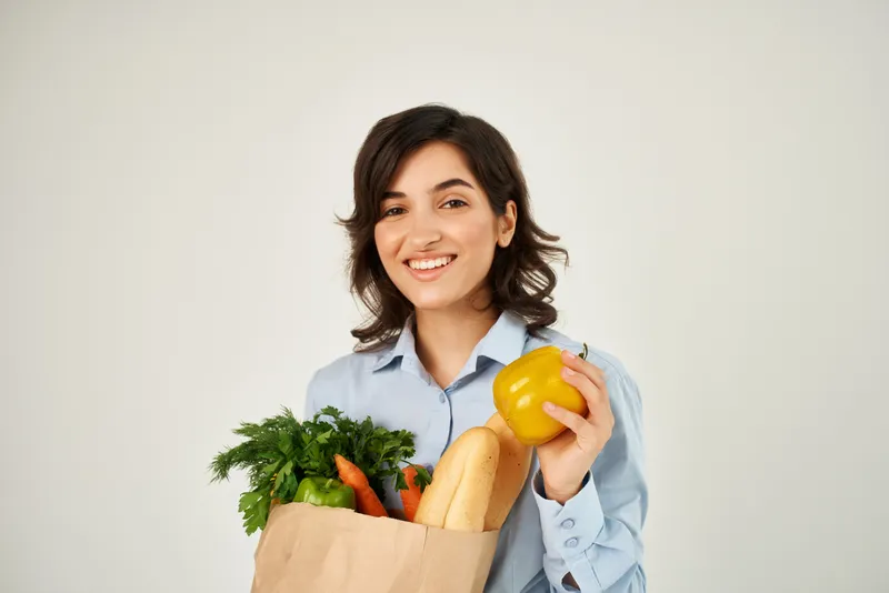 Симпатичная брюнетка в голубой рубашке с продуктовой сумкой, органическая еда