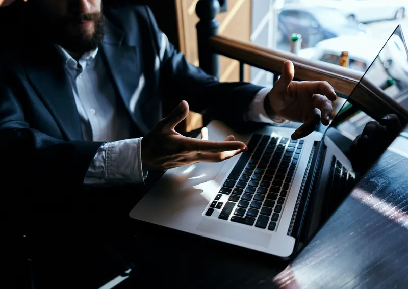 Мужчина сидит в кафе перед ноутбуком и работает, используя интернет-технологии