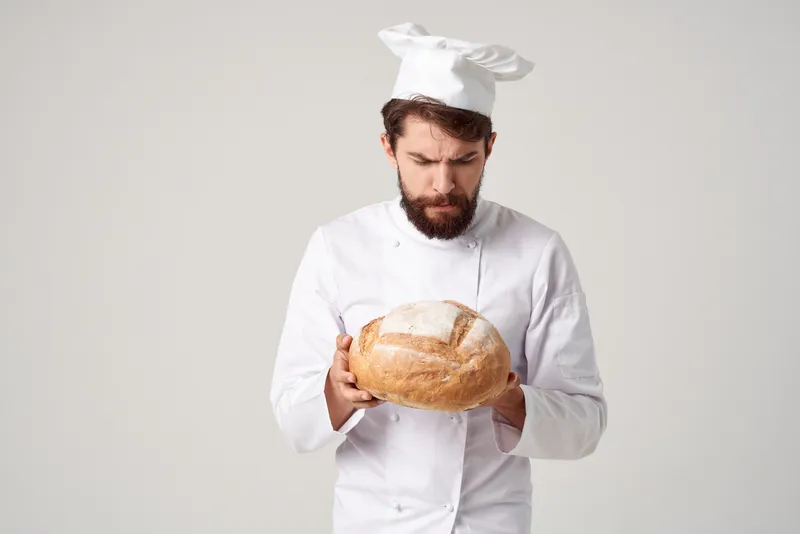 Бородатый мужчина-повар на кухне, работа с хлебобулочными изделиями на изолированном фоне