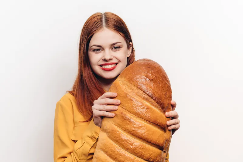 Женщина с буханкой хлеба, в желтой рубашке, с рыжими волосами, обрезанный вид