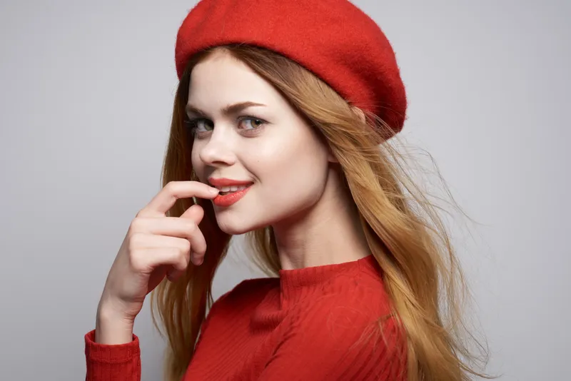 Красивая женщина делает забавный жест рукой, её красные губы привлекают внимание, на изолированном фоне