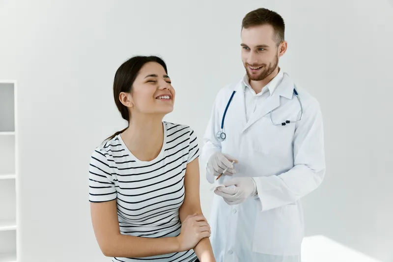 Врач-мужчина рядом с пациентом, делающий вакцинацию