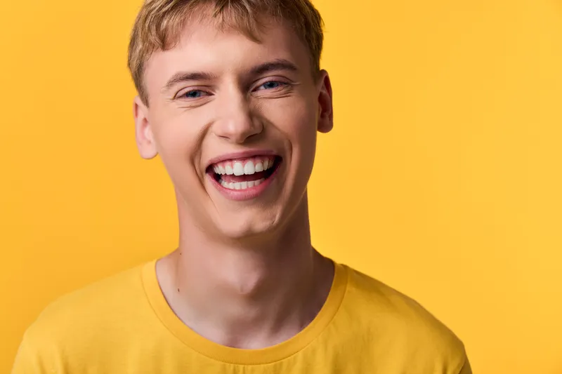 Smiling man wearing a yellow shirt against a vibrant yellow backdrop, radiating happiness, energy and friendly vibes suitable for lifestyle, wellness and positivity campaigns