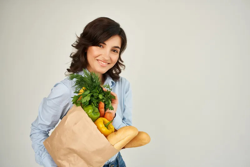 Весёлая женщина с пакетом продуктов из супермаркета: шопинг, образ жизни