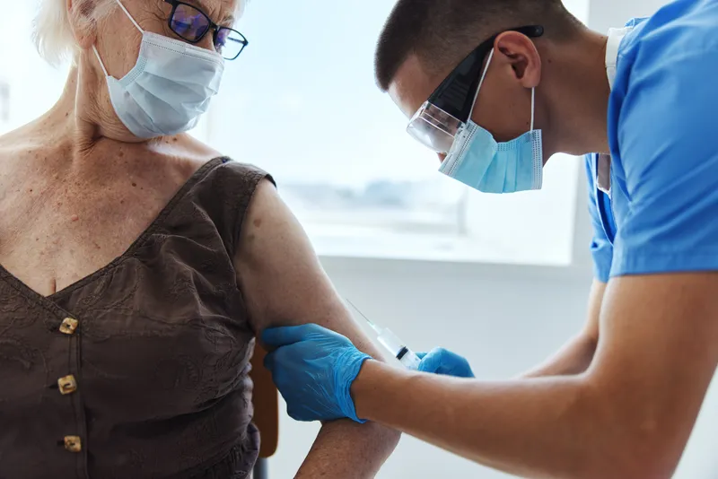Врач-мужчина делает прививку от COVID-19, паспорт вакцинации, пандемия коронавируса