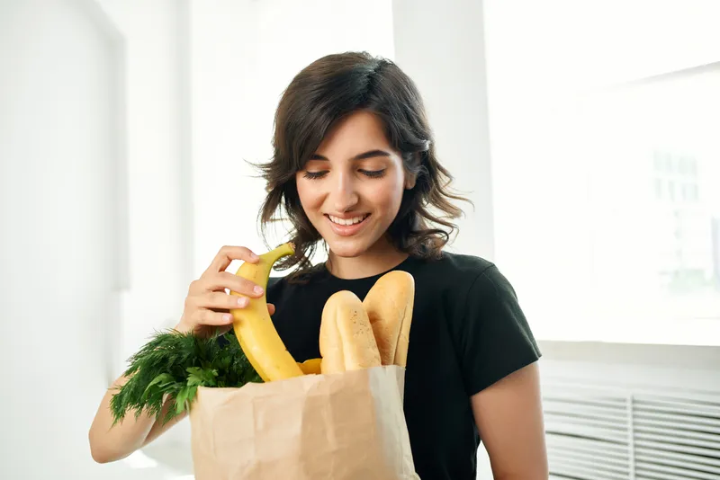 Брюнетка с пакетом продуктов дома, доставка здоровой еды
