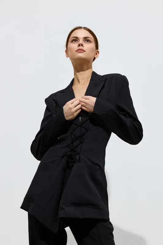 fashion woman wearing black tailored blazer looking upward confidently, minimalist style with sharp shadows and soft natural lighting, contemporary beauty portrait