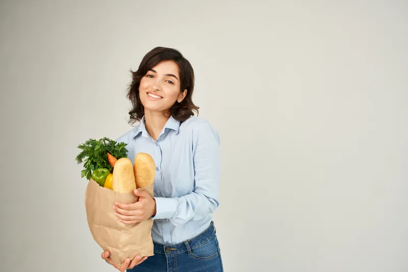 Женщина с пакетом продуктов, здоровой едой, овощами, совершающая покупки в супермаркете