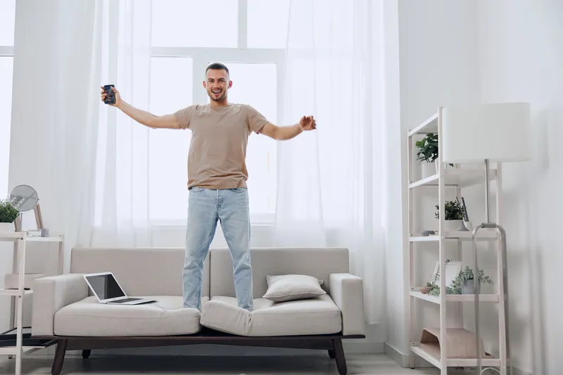 Happy man celebrating his digital detox journey, embracing work-life balance with joy, while practicing self-care in a cozy living space.
