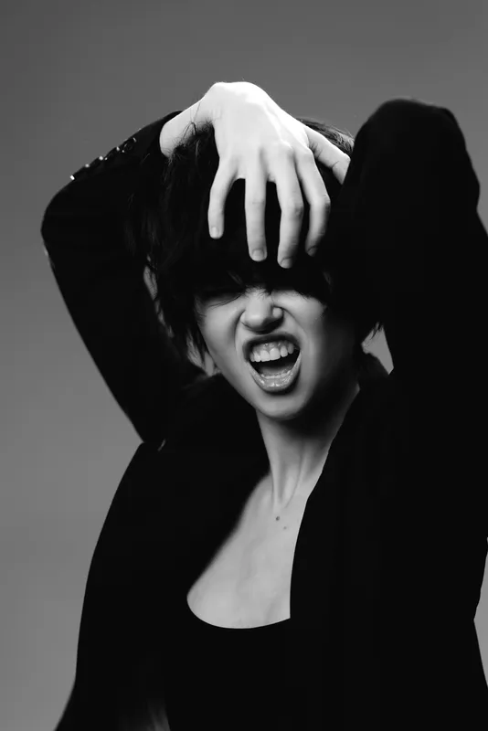 Black and white portrait of a woman expressing anger with dramatic pose and intense emotion.