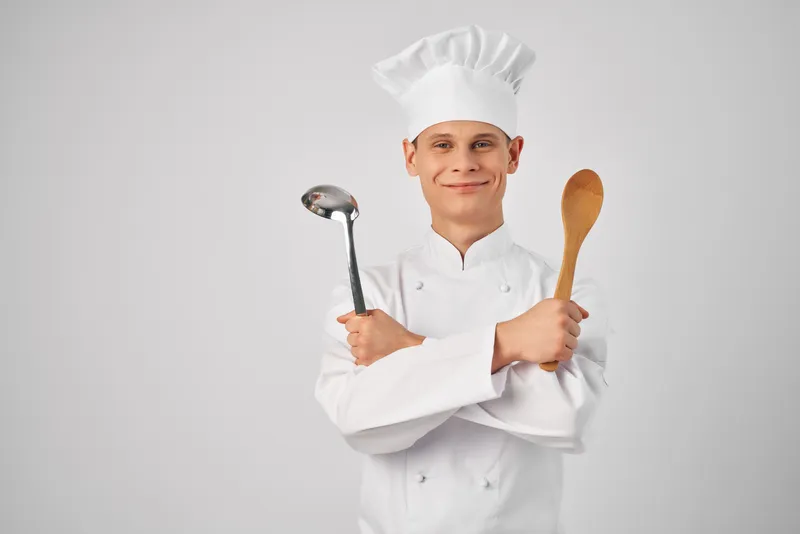Повар с половником и деревянной ложкой в руках занимается кухонной работой