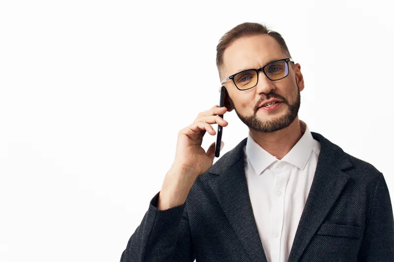 A professional man in business attire speaks on a smartphone against an isolated colored background, conveying confidence, focus, and clear communication.