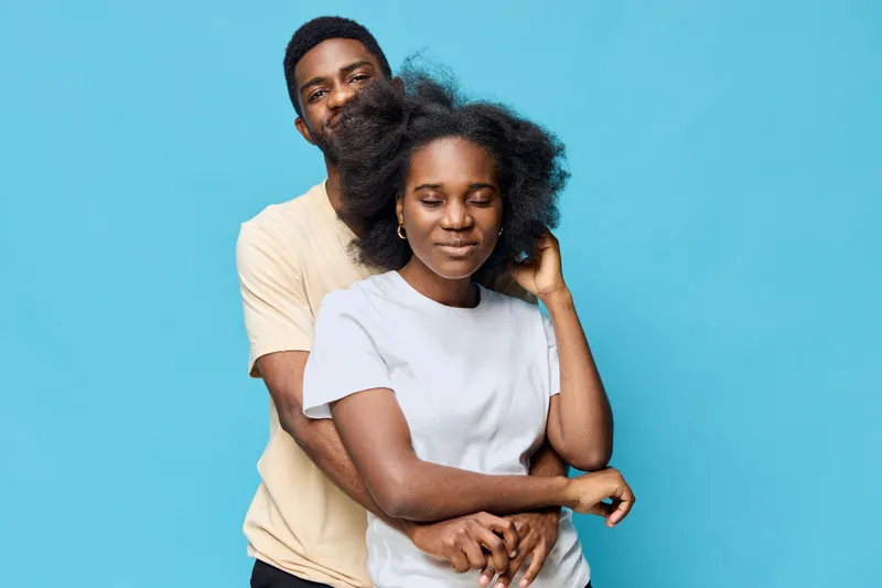 A joyful couple embracing against a bright blue background, showcasing love and connection, perfect for relationship themes, family bonding, and happiness concepts