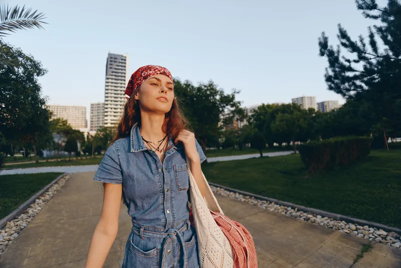 lifestyle woman in modern boho-western denim street style wearing red bandana and casual accessories, relaxed outdoor urban film color mood