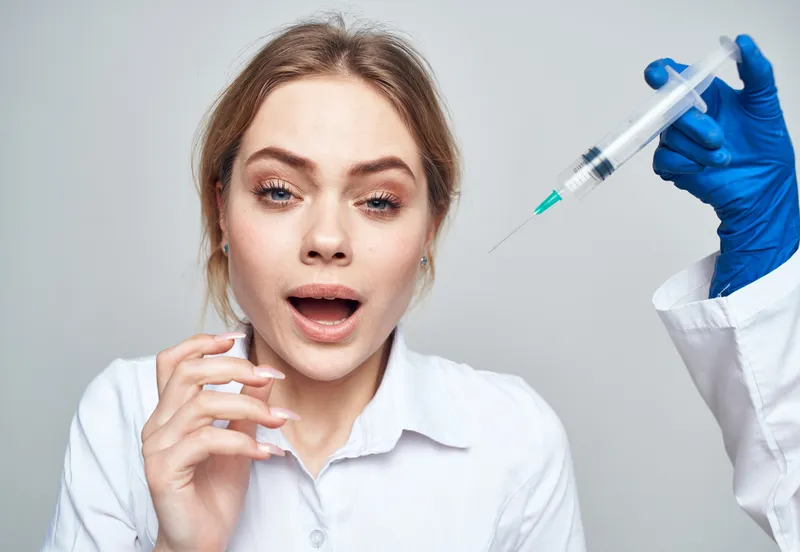 Пациентка улыбается, а в руках врача шприц для инъекции ботокса