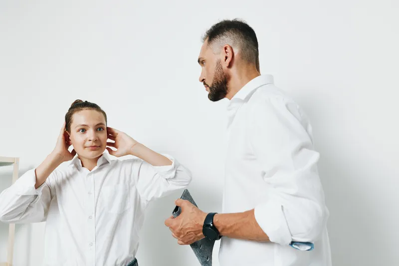 A professional businessman and colleague in white shirts stand against an isolated colored background, showing calm confidence, focus, and collaborative mood.