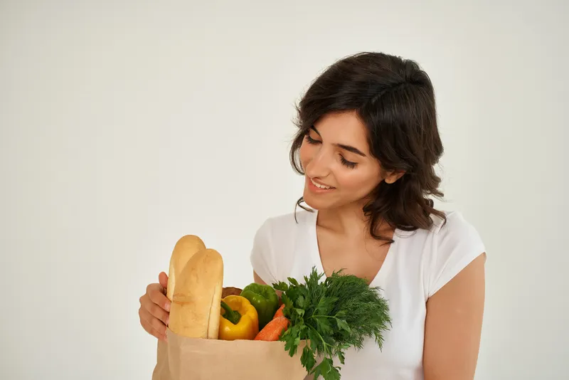 Женщина с пакетом продуктов, совершающая покупки и доставку овощей