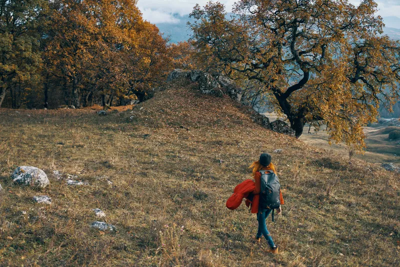 Женщина-туристка гуляет на природе по осеннему лесу в горах