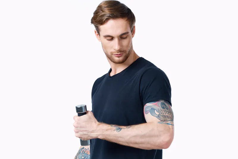 Спортсмен в черной футболке с гантелями на белом фоне, вид сбоку