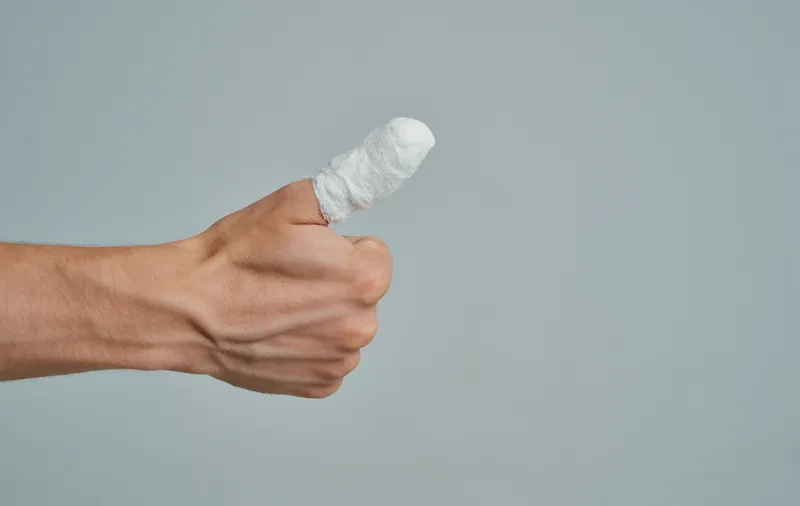 Мужчина в белой футболке, сломанный палец, перевязан, медицина