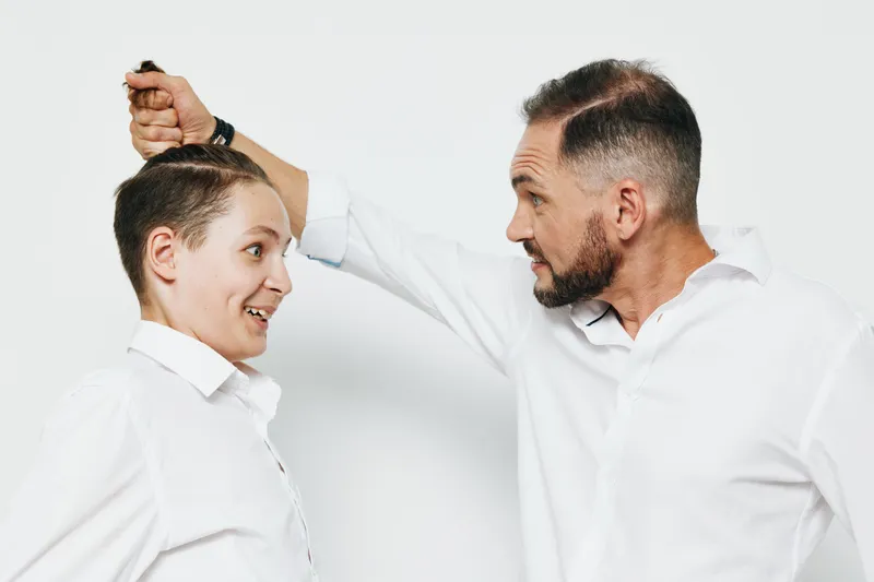 A professional business man interacts with a colleague in a light hearted moment, showcasing leadership and teamwork. Isolated white background emphasizes confident emotion and dynamic connection.