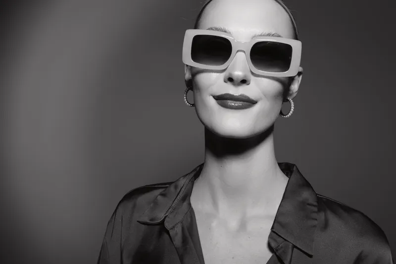 Portrait of a fair skinned Caucasian woman wearing large sunglasses and hoop earrings in black and white. Concept of fashion, style, and confident attitude.