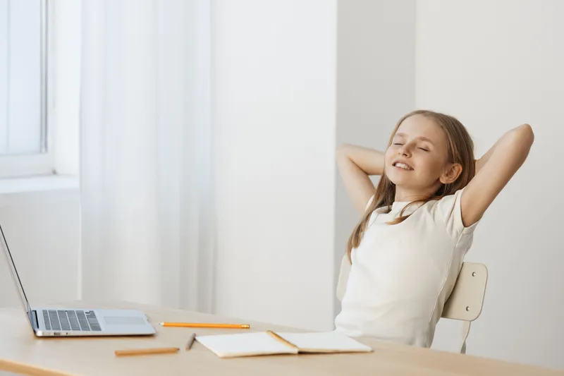 Relaxed girl enjoying a moment of peace at her study desk, bright and airy atmosphere, soft colors, promoting creativity and focus
