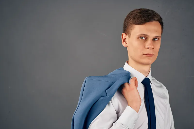 Деловой мужчина в рубашке с галстуком, пиджак на плече, излучающий уверенность в офисе