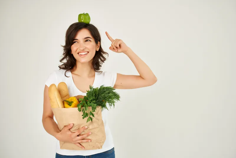 Женщина с пакетом продуктов в супермаркете на светлом фоне