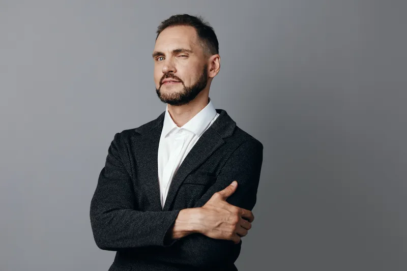 Portrait of a professional man in a tailored blazer against an isolated grey background, conveying calm confidence and poised emotion suitable for business themes.