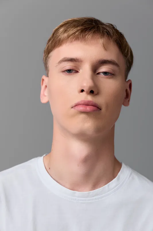 Man, young, face, white tshirt, neutral background, studio lighting, close up headshot with calm expression, minimal clean style for stock photography and versatile use in fashion and branding