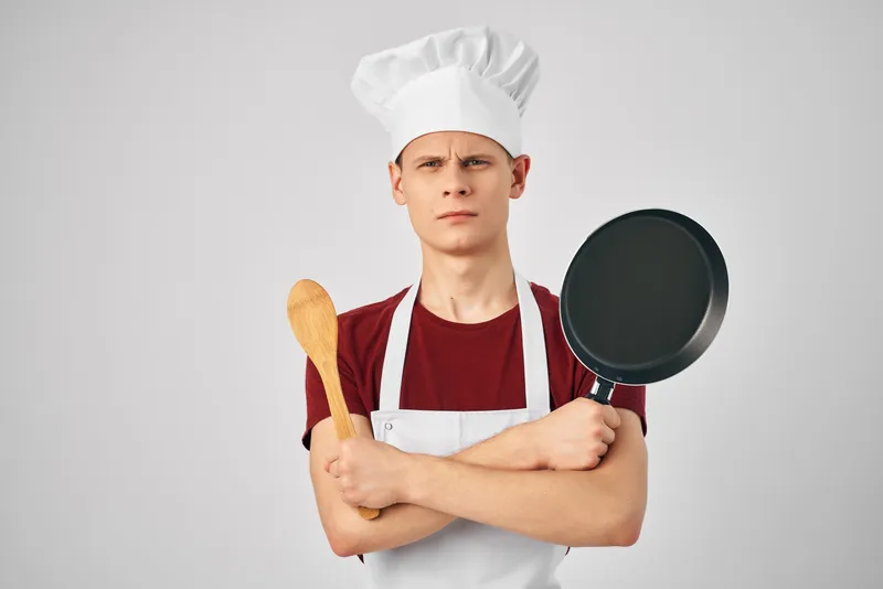 Повар-мужчина с кухонной утварью занимается приготовлением блюд в ресторане