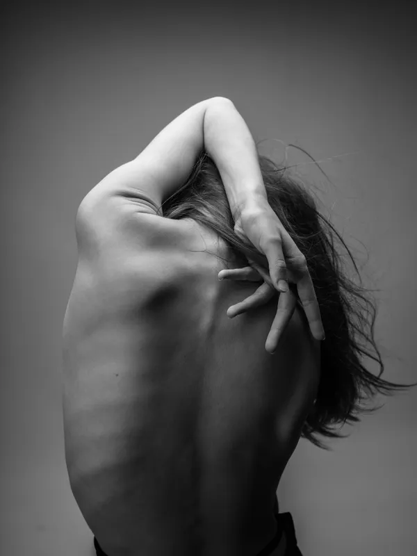 Обнаженная спина женщины с поднятой рукой в черно-белом свете