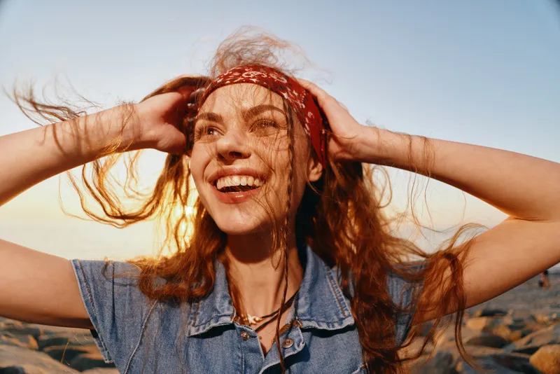 lifestyle woman in modern boho-western denim street style smiling with red bandana and curly hair under warm natural light film color mood
