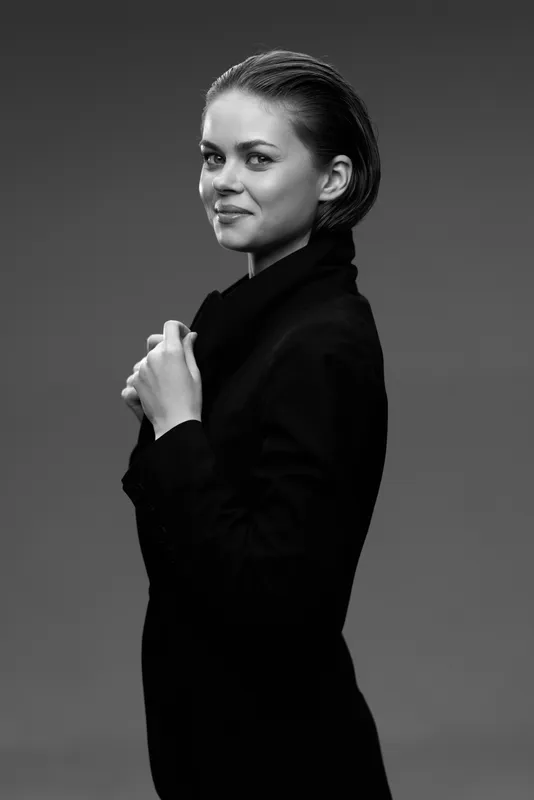 Young woman in black turtleneck posing confidently in black and white portrait with soft lighting and neutral background