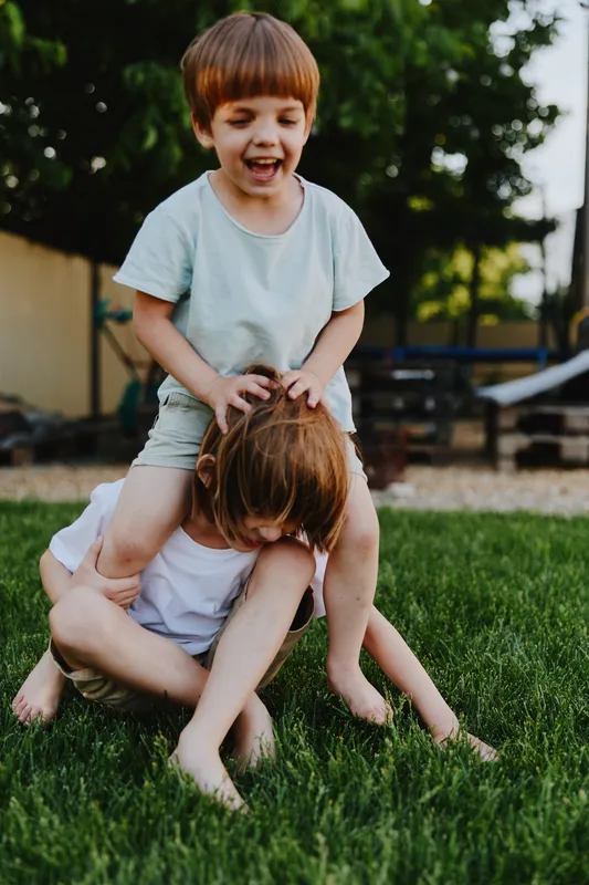 Joyful children playing on the grass, capturing a carefree moment filled with laughter, friendship, and outdoor fun in a sunny setting. ###