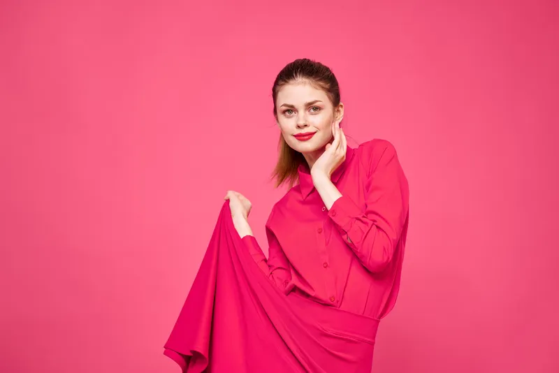 Женщина на розовом фоне в модной одежде, с ярким макияжем и прической, модель, копировальное пространство