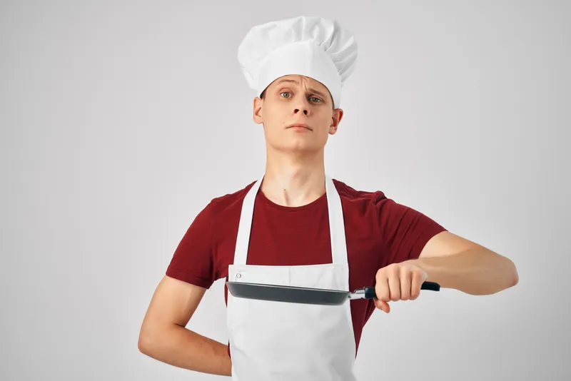 Мужчина-повар на кухне занимается приготовлением пищи в ресторане