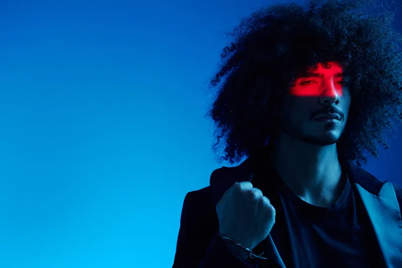 Модный портрет мужчины с кудрявыми волосами на синем фоне