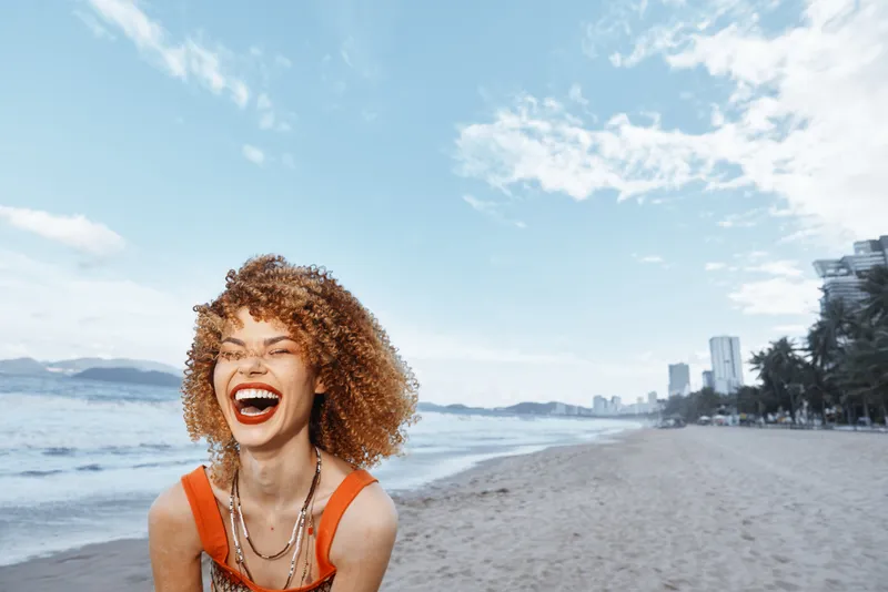 Улыбающаяся женщина на пляже, воплощающая образ жизни хиппи