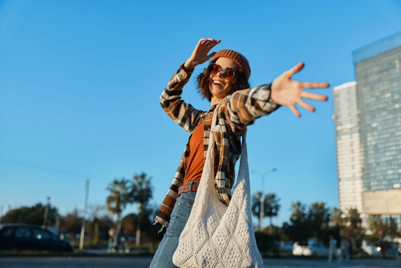 Woman smile joyful urban candid lifestyle fashion happiness captured with authenticity and golden hour glow, carefree bohemian outfit reaching camera, emotional storytelling and mindful living vibe.