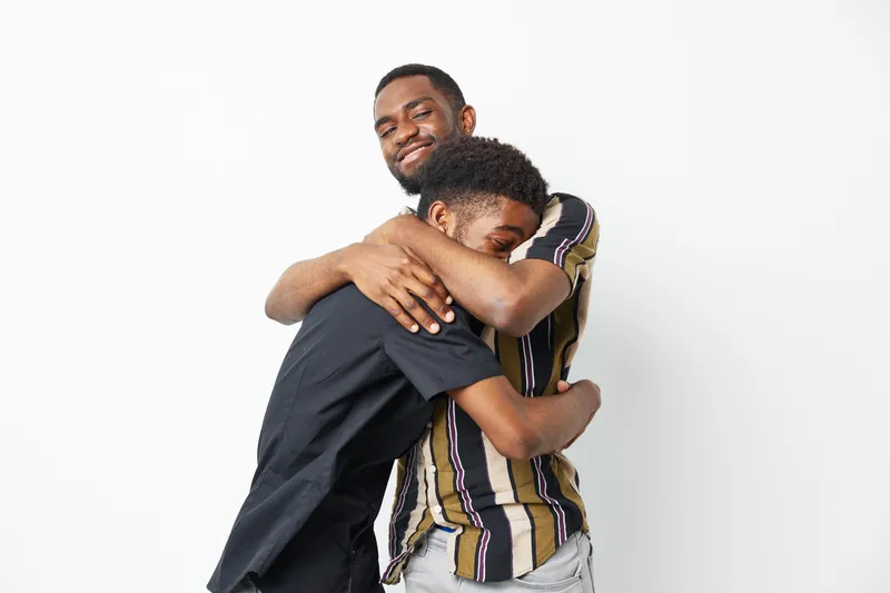 Embracing black men sharing a joyful moment, showcasing love and connection in a vibrant setting that captures the essence of friendship and support.