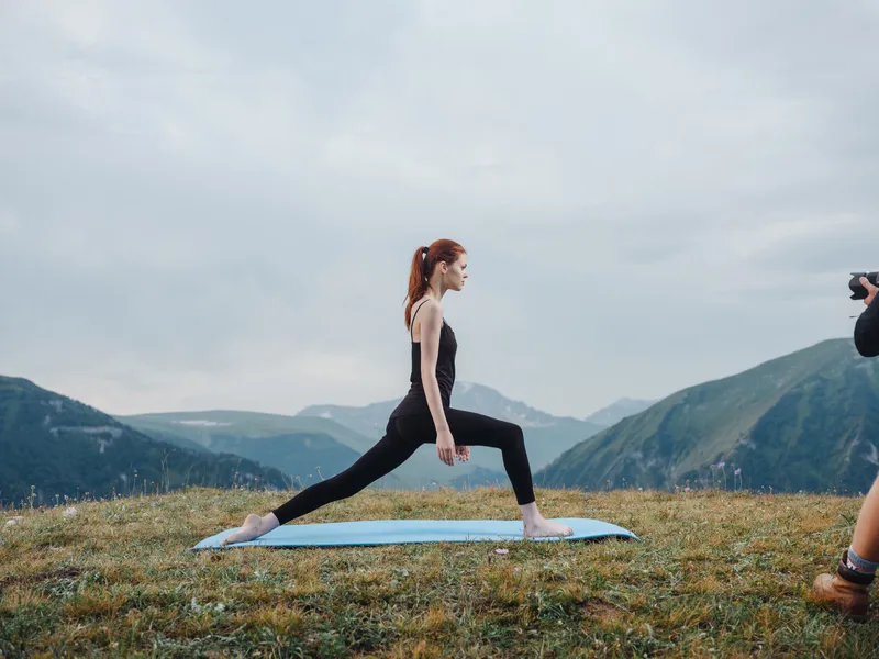 Спортивная женщина занимается йогой и медитацией в горах, наслаждаясь природой и свежим воздухом