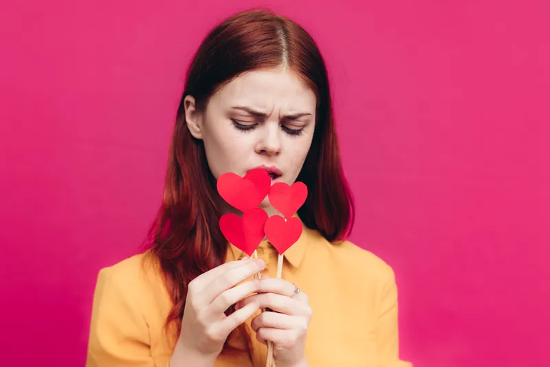 Подарки ко Дню святого Валентина: женщина с сердечком на палочке на розовом фоне