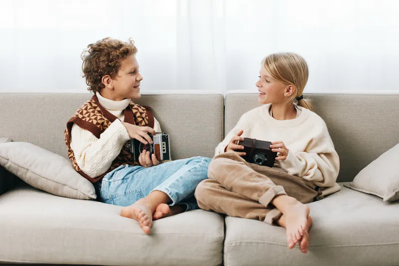 Authentic scene of children at home, two siblings share a playful moment, sitting on a cozy sofa, exploring games with calm focus and wholesome lifestyle vibes.